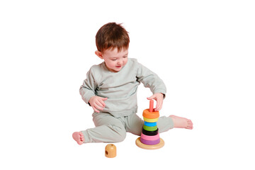 Happy toddler baby plays with a pyramid on a studio, isolated on white background. Child boy puts...