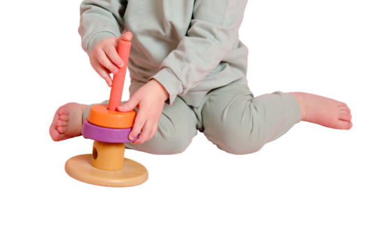 Happy toddler baby plays with a pyramid on a studio, isolated on white background. Child boy puts wooden rings on a toy pyramid, isolated on white background. Kid age one year eight months