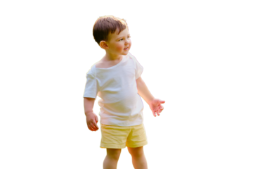 A happy child is standing on the green grass in the park, a full-length photo, isolated on white background. Smiling baby in nature in the rays of the setting sun. Kid aged about two years
