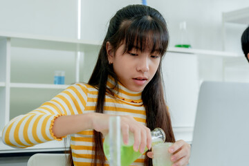 Cute asian schoolgirl Scientifically experimenting with mixing colors in test tubes Learning...