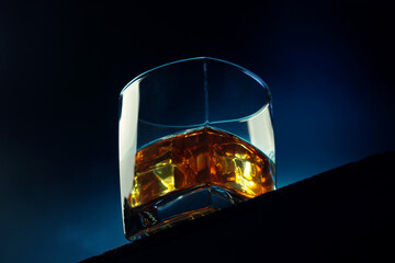 Glass of whiskey with ice on a dark background. Alcoholic drink