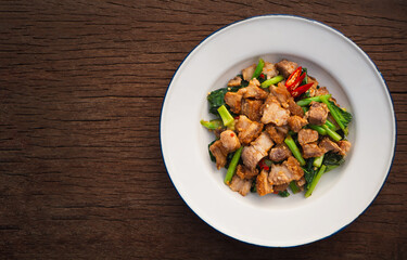 Top view of stir fried crispy pork with kale and oyster sauce in plate on wooden table. Asia Food
