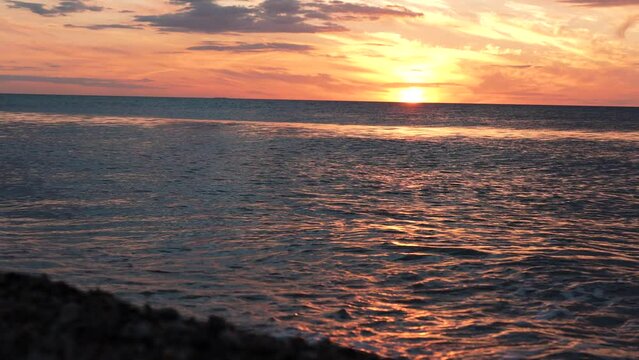 Red sunsets over sea video 4K. The sun touches horizon. Red sky, yellow sun and amazing sea. Summer sunset seascape. Atlantic Ocean beach sunsets. The sun in spindrift clouds Fantastic natural sunsets