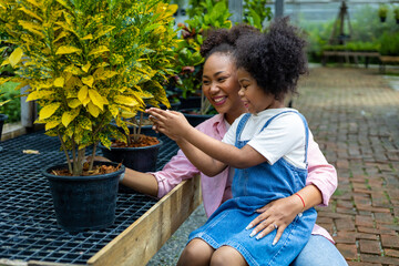 African mother and daughter is choosing tropical and ornamental plant from the local garden center nursery during summer for weekend gardening and outdoor concept