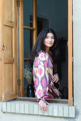 Beautiful fashion model, girl in traditional Uzbekistan fashion dress with ikat pattern in window. Tashkent, Uzbekistan