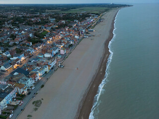 Fototapeta na wymiar Dramatic aerial view of a dusk view of the popular Suffolk coastal town of Aldeburgh. Showing the orange street lights and lit dwellings.