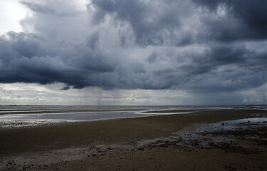 Regenwolken ziehen vorbei am Wattenmeer von Föhr bei Ebbe.