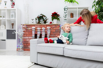Mom and her little son stay in a room decorated with Christmas ornaments