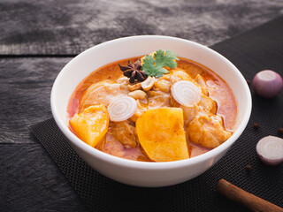 Massaman curry with chicken and potatoes in bowl on wooden background. Thai Food