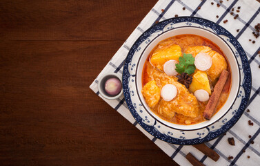 Top view of massaman curry with chicken and potatoes in bowl on wooden background. Thai Food