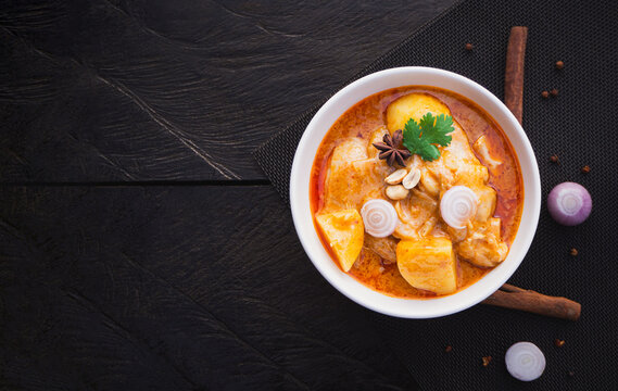 Top view of massaman curry with chicken and potatoes in bowl on wooden background. Thai Food