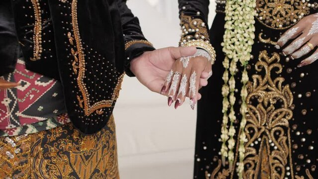 The bride and groom celebrated the Javanese Indonesian traditional wedding by holding hands