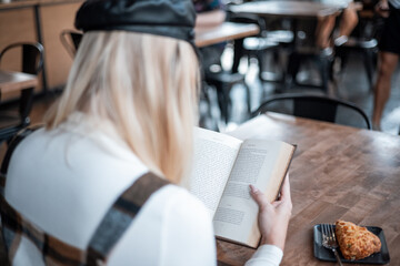 Close up of woman reading book, looking over shoulder in a coffee shop