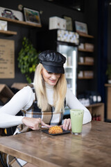 Woman sitting in coffee shop cutting a scone with her fork