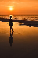 Woman on the seashore in a beautiful evening scenery. Girl walking on the beach with the setting sun in the background. Photo taken at the Baltic Sea in Leba, Poland. - 658740163