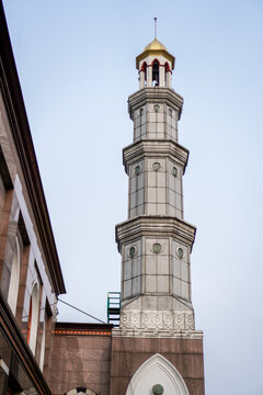 The mosque building with a golden yellow dome appears under a clear sky. the tower is inscribed in Aran language. 