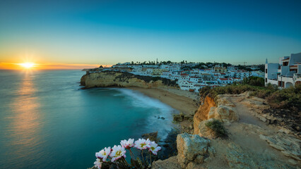 Obraz premium View of Carvoeiro fishing village with beautiful beach, Algarve, Portugal. View of beach in Carvoeiro town with small houses on coast of Portugal at sunset (long exposure)