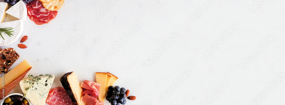 Aufkleber selection of charcuterie cheeses, meats and appetizers. above view corner border on a white marble b