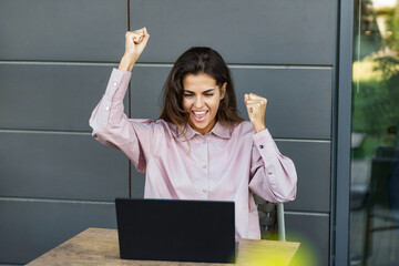 Successful businesswoman working remotely outside the office, sitting in a cafe is satisfied with...