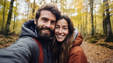 happy smiling couple taking a selfie in a forest in autumn