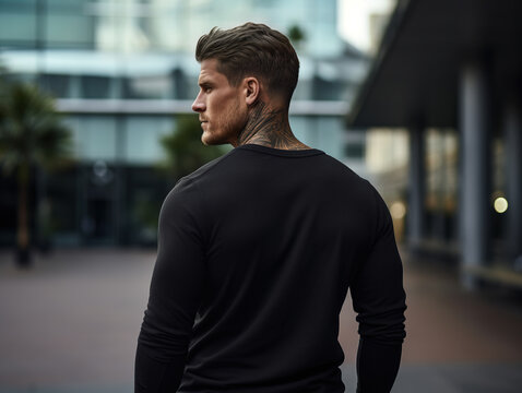 Back view handsome man in black blank sweatshirt on city street background Mockup for printing and branding