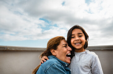 Happy Hispanic child enjoying time with grandmother at house rooftop