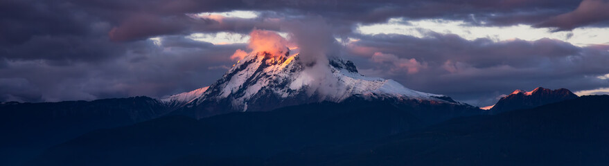 Mountain Peak Covered in clouds and snow. Dramatic Sunset Sky. Aerial Nature Background.