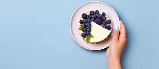 Woman s perspective of holding cheesecake slice with blueberries on plate With copyspace for text - Powered by Adobe