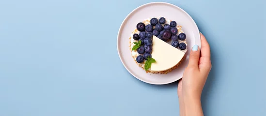 Foto op Plexiglas Woman s perspective of holding cheesecake slice with blueberries on plate With copyspace for text © 2rogan