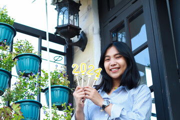 happy asian young woman hipster looking to camera with holding 2024 number candle celebrating new...