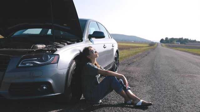 Woman feel frustrated as car breakdown, sits by vehicle, gazing at sky, and waiting help from fellow drivers or service provider, side view