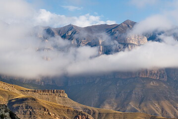 Russia. The Elbrus region. The high mountain peaks of the North Caucasus are surrounded by morning misty clouds hovering at different levels of inaccessible rocks.