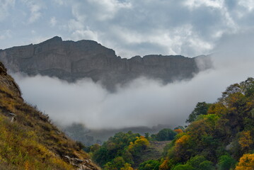 Russia. The Elbrus region. The high mountain peaks of the North Caucasus are surrounded by morning misty clouds hovering at different levels of inaccessible rocks.