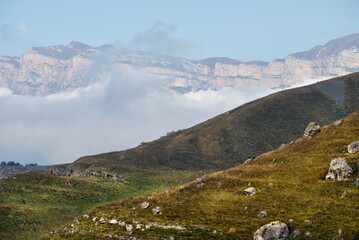 Russia. The Elbrus region. The high mountain peaks of the North Caucasus are surrounded by morning misty clouds hovering at different levels of inaccessible rocks.