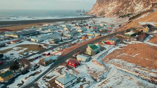 Aerial view Small town city of Vik including its famous picturesque church on hills at sunrise in winter, Reynisfjara Beach, Iceland.
