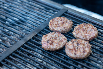 Chef making burger meat at the open air restaurant grill. Festival food, fast food restaurant , cooking meatballs on the grill with tongs in hand