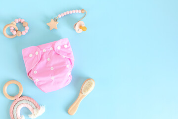 Flat lay with reusable cloth baby diaper, toys and accessories. Eco friendly nappy on blue pastel background. Sustainable lifestyle, zero waste idea
