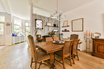 a dining room with wood flooring and white walls there is a large wooden table surrounded by chairs in the room