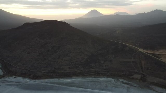 Camera rising up from Lake Salinas Salt flats to reveal Chachani Volcano with the sunsetting behind the volcano