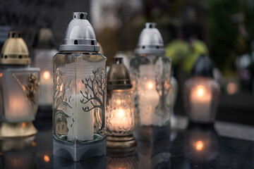 Lit grave candles with botanical motifs on a tombstone — Poland, November 1, All Saints’ Day...