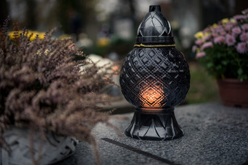 Lit decorative grave candles by a tombstone — Poland, November 1, All Saints’ Day (also known...