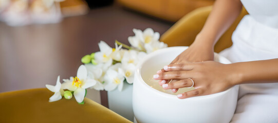 Obraz na płótnie Canvas A woman's hand receiving a natural and elegant manicure treatment at a spa or salon, showcasing the meticulous care and attention to detail.