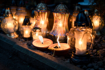 Lit grave candles on a tombstone on a November evening with soft warm candlelight — Poland,...