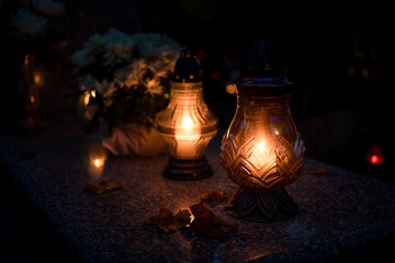 Lit grave candles on a tombstone on a November evening with soft warm candlelight — Poland,...