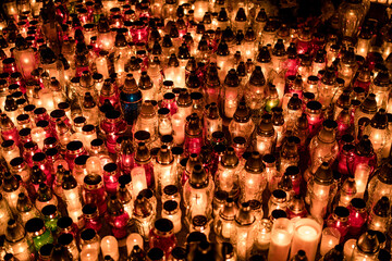 Fototapeta premium Many lit grave candles at the base of a cemetery monument — Poland, November 1, All Saints’ Day (also known as All Souls’ Day / Day of the Dead)