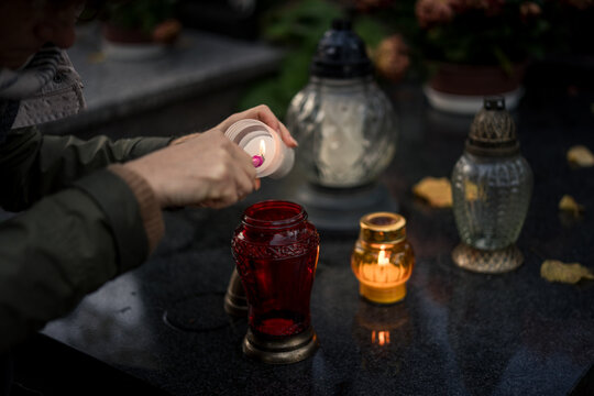 Hand lighting and placing a grave candle at a tombstone, close-up, Poland, November 1 - All Saints' Day (also known as All Souls' Day, Day of the Dead)