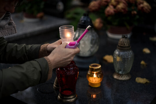 Hand lighting and placing a grave candle at a tombstone, close-up, Poland, November 1 - All Saints' Day (also known as All Souls' Day, Day of the Dead)
