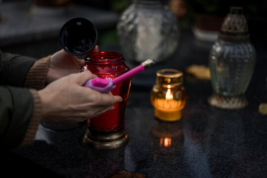 Hand lighting and placing a grave candle at a tombstone, close-up, Poland, November 1 - All Saints' Day (also known as All Souls' Day, Day of the Dead)