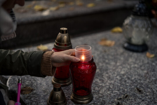 Hand lighting and placing a grave candle at a tombstone, close-up, Poland, November 1 - All Saints' Day (also known as All Souls' Day, Day of the Dead)
