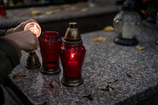 Hand lighting and placing a grave candle at a tombstone, close-up, Poland, November 1 - All Saints' Day (also known as All Souls' Day, Day of the Dead)